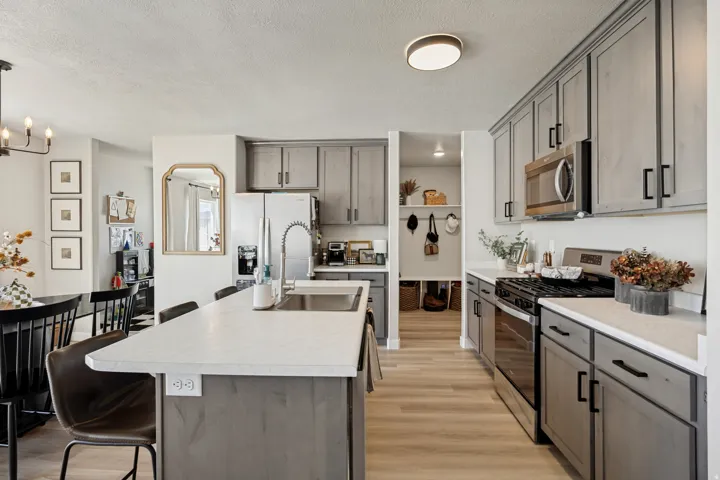 Kitchen featuring a central island with countertop seating, light wood-finish flooring, stainless steel appliances, grey cabinetry, and white countertops