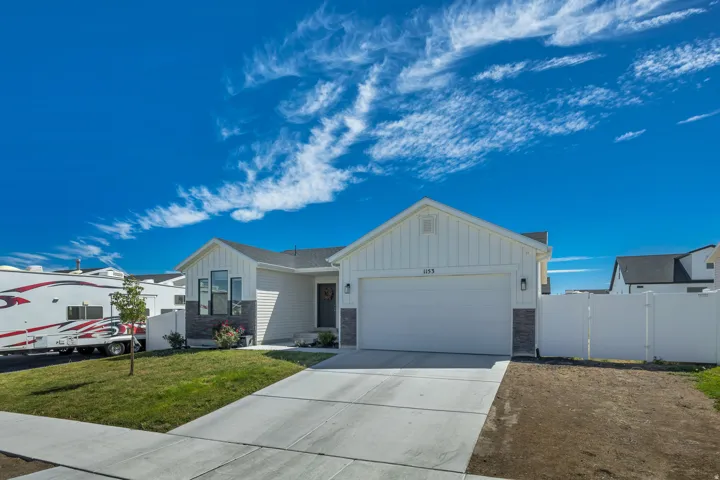White siding exterior with a dark shingle roof, integrated garage, concrete driveway, and front landscaping