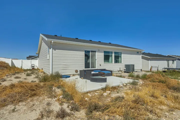 Rear exterior featuring horizontal siding, a sliding glass door, multiple large windows, and a concrete patio