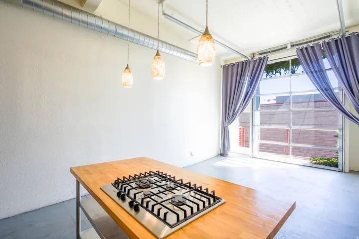 Exposed ceiling ductwork, three pendant light fixtures, and a glass paneled roll-up door