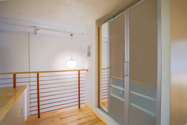 Hardwood flooring, contemporary metal and wood railing, modern pendant lighting, track lighting, and built-in frosted glass wardrobes