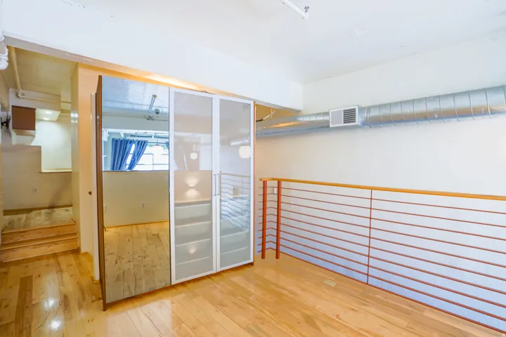 Hardwood flooring, custom closet system with mirrored panels, and industrial-style exposed ductwork