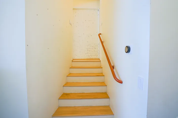 Wood-finish stair treads with white risers and a contrasting wood handrail