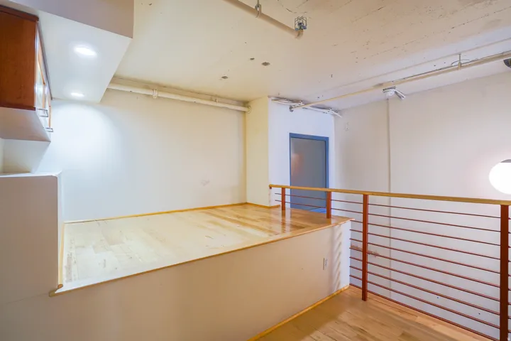 Loft area with wood-finish flooring, recessed lighting, and a metal and wood railing