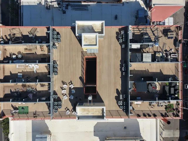Expansive rooftop deck featuring wood-finish flooring, metal railings, and multiple distinct sections
