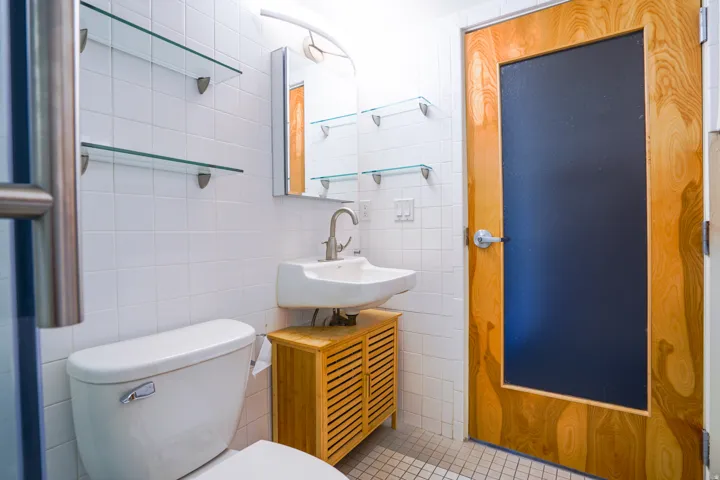White tile walls featuring glass shelving