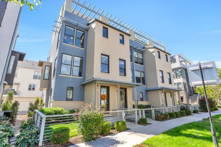 Contemporary townhome with a multi-level design, featuring a light brick facade and blue siding