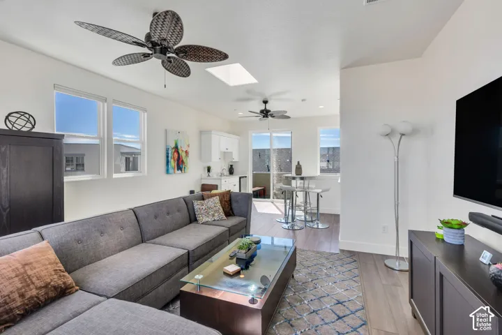 Recessed lighting, wood-finish flooring, multiple windows, and dual ceiling fans enhance this open-concept space