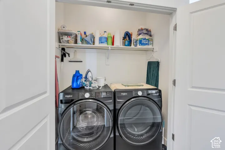 Built-in laundry closet with a side-by-side washer and dryer, upper storage shelf, and white paneled doors