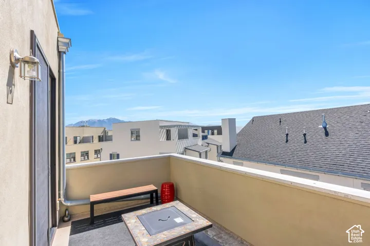 Outdoor balcony with a stucco exterior, gray tile flooring, and a low privacy wall