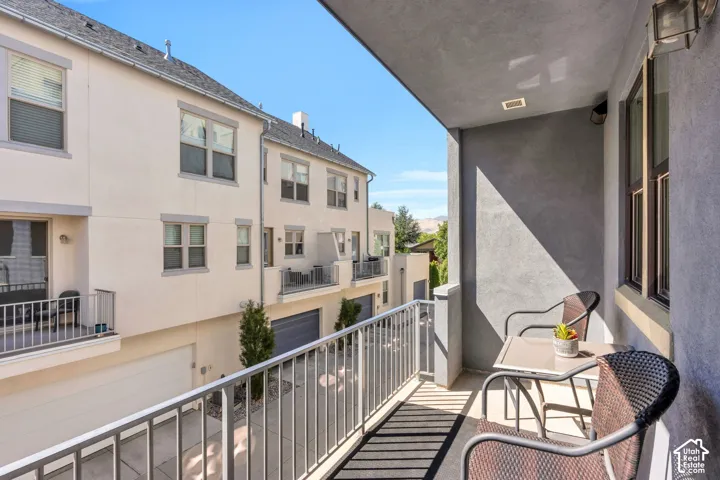Private balcony with metal railing, stucco exterior, and recessed lighting