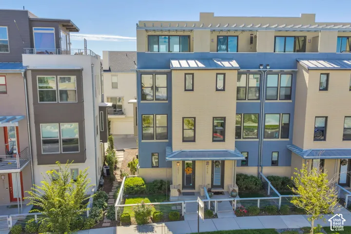Modern multi-story townhouse with a light-colored stucco exterior and contrasting blue accent panels