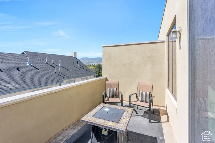 Private balcony with a stucco finish, outdoor wall lantern, and distant mountain scenery