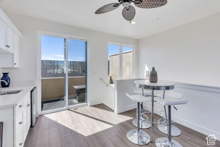 Wood-finish flooring, white cabinetry, integrated sink, and sliding glass door