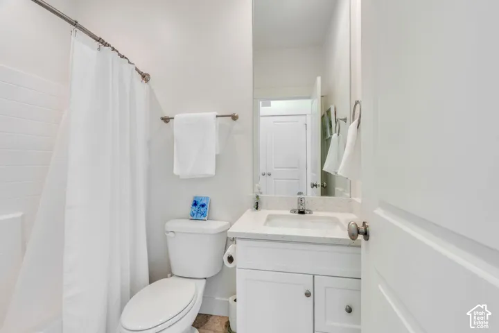 White subway tile shower surround with a fixed showerhead, single vanity with a white countertop and integrated sink, and brushed nickel hardware