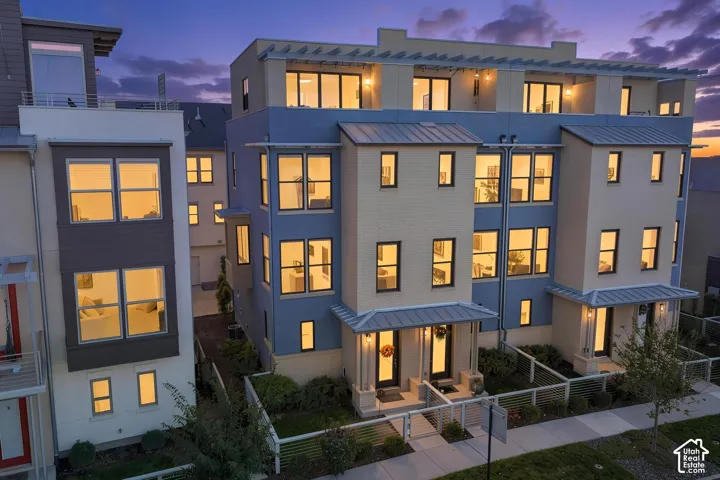 Modern architectural style with multiple large windows, metal roof accents, and an upper-level balcony