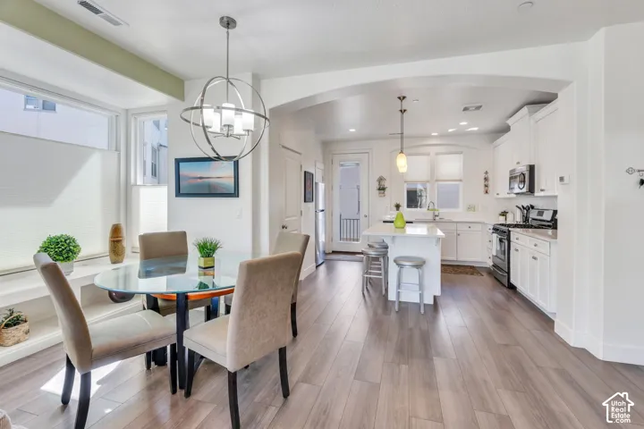 Open-concept living space with wood-finish flooring, white cabinetry, a kitchen island, and a built-in window bench