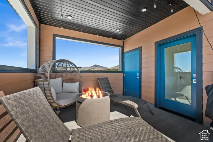 Covered outdoor balcony with a black slatted ceiling, recessed lighting, and a panoramic view of the mountains
