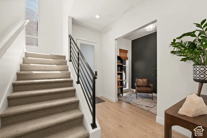 Carpeted staircase with contemporary black metal railing and view of office