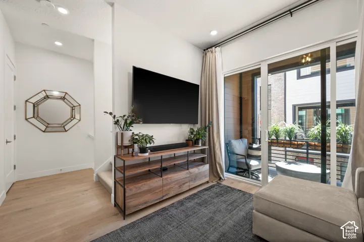 Recessed lighting throughout, wood-finish flooring, sliding glass door, private balcony, and sleek railing