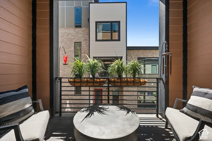 Balcony with horizontal metal railing, wood-look siding, and a partial view of contemporary architecture