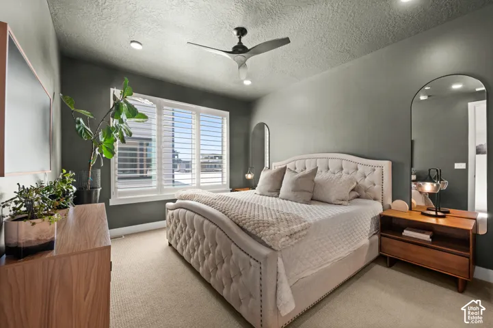 Primary bedroom features recessed lighting, large windows, ceiling fan, and carpeted floors