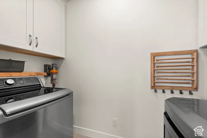 White upper cabinetry with brushed nickel hardware, wood-finish shelving, and a wall-mounted wooden drying rack with hooks