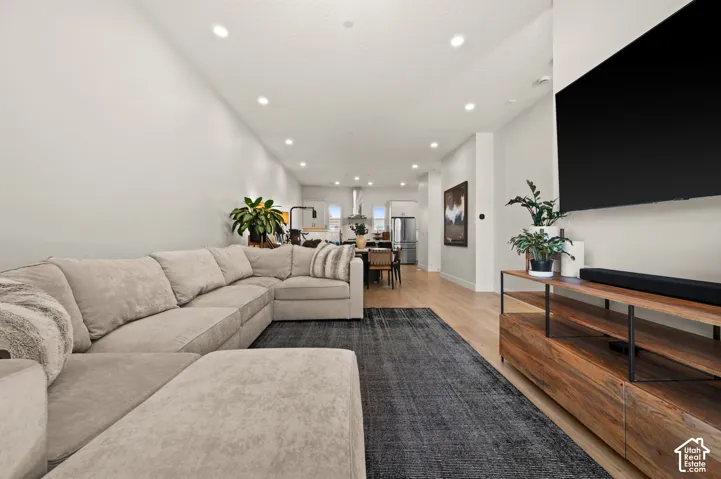Recessed lighting illuminates the open-concept living space with light wood-finish flooring