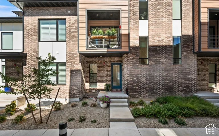 Brick and horizontal siding exterior with a private balcony, a teal entry door, and concrete steps