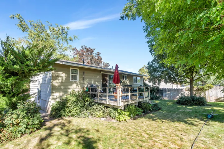 Expansive backyard featuring a wood deck, established perimeter fencing, and mature trees