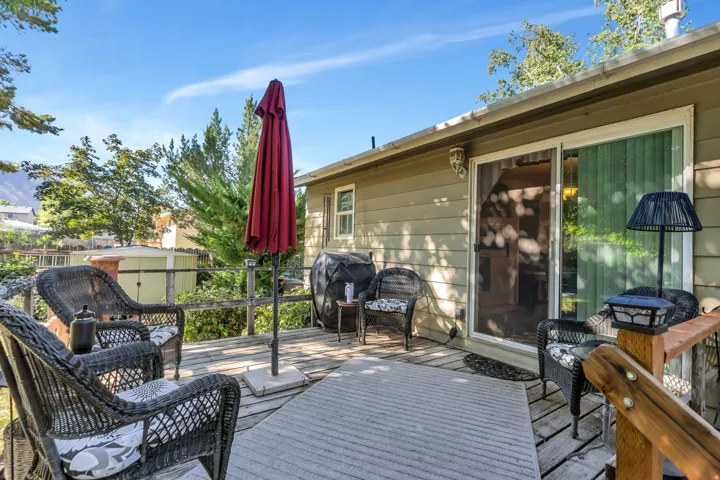 Spacious outdoor deck with wood flooring and railing, featuring a sliding glass door and exterior siding