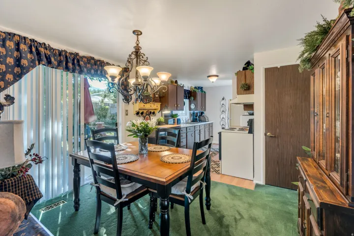 Dining area featuring a decorative chandelier, green carpet, and sliding glass door