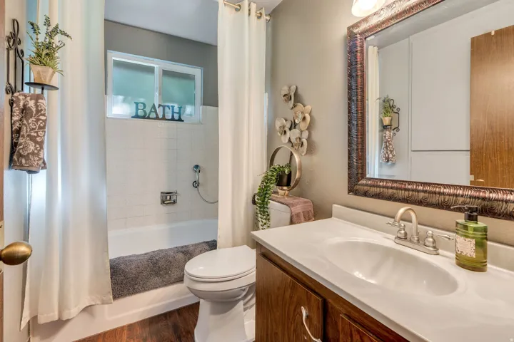 Wood-finish flooring with a white vanity featuring an integrated sink