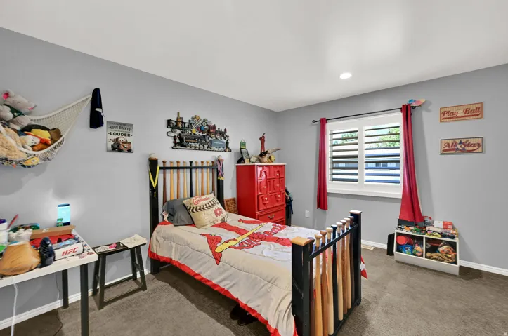 Recessed lighting, window with white louvered shutters, light gray wall paint, and gray carpet flooring