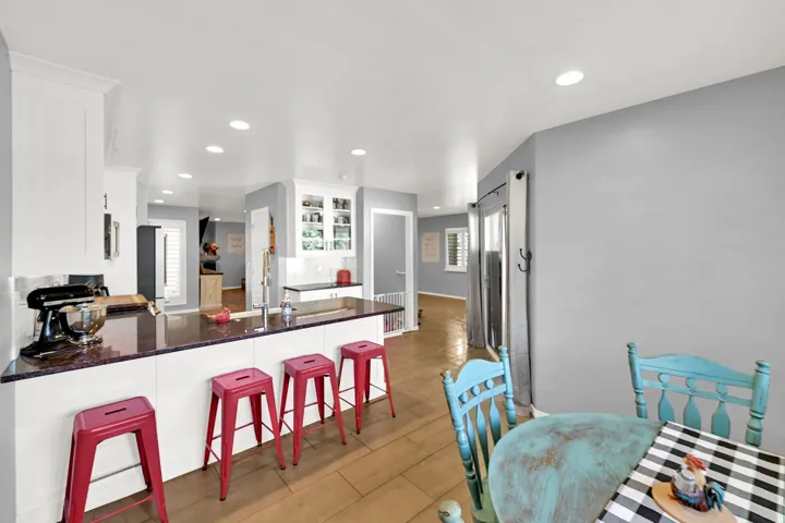 Open-concept kitchen featuring white cabinetry, a brown countertop, recessed lighting, and wood-finish flooring