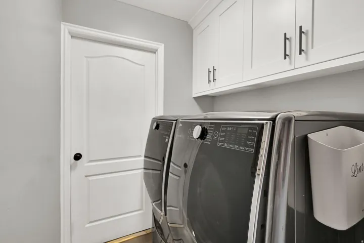 White shaker-style cabinetry with dark hardware and a white interior door