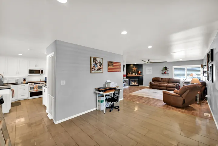 Open concept living area featuring wood-finish flooring, recessed lighting, and a kitchen with white cabinetry and stainless steel appliances