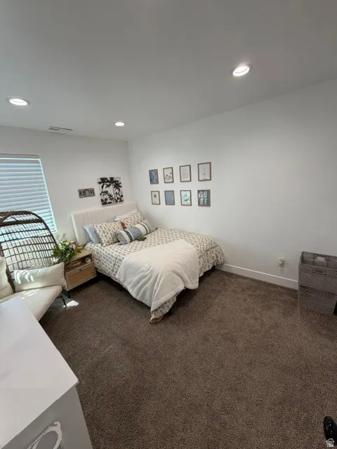 Recessed ceiling lighting, white walls, textured carpeting, and a window with blinds