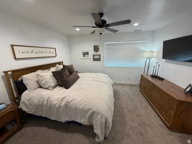 Recessed lighting, ceiling fan, window with blinds, wood-finish flooring, and a wooden headboard
