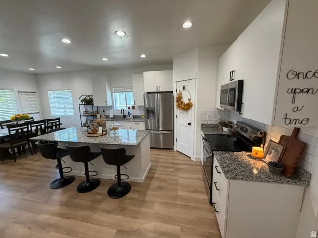 Kitchen featuring wood-finish flooring, recessed lighting, and white cabinetry