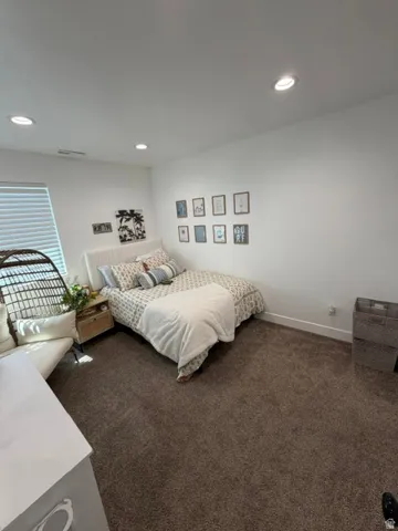 Recessed ceiling lighting, white walls, textured carpeting, and a window with blinds