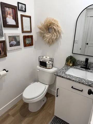 White vanity with black hardware, granite countertop, rectangular undermount sink, and black faucet