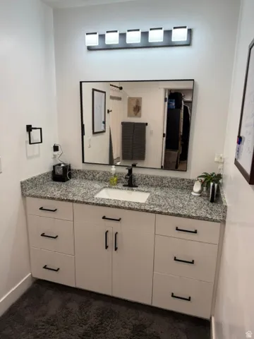 White vanity with black cabinet hardware, granite-style countertop, and rectangular undermount sink