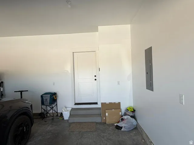 Interior access door with panel detailing, concrete steps, and a visible electrical panel