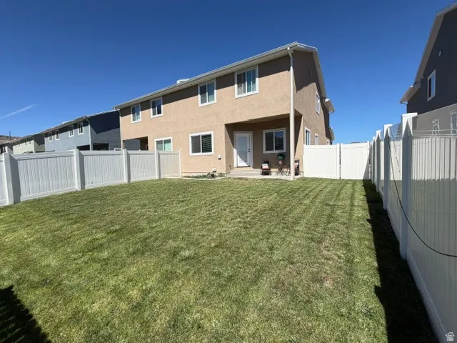 Expansive backyard featuring a manicured lawn, full perimeter fencing, and a concrete patio