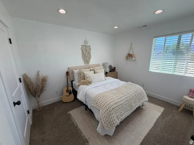 Recessed lighting illuminates neutral-toned carpeting and white walls