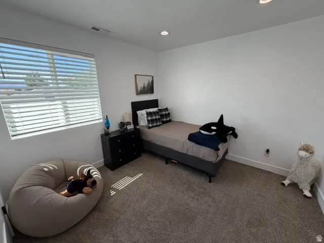 Recessed lighting, large window with blinds, neutral carpeting, white walls, and built-in white baseboards