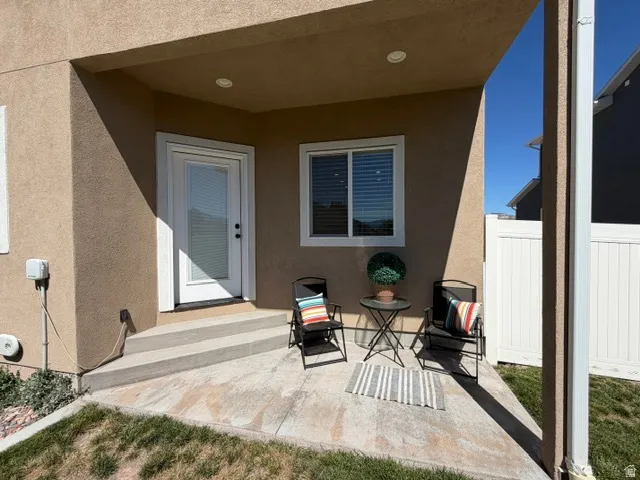 Covered patio with a concrete surface, white privacy fencing, and a glass-paneled exterior door