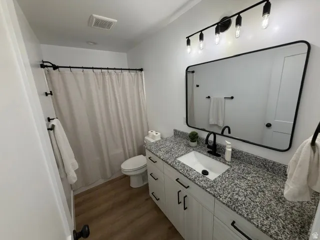 Bathroom featuring a white vanity with black hardware, a granite-look countertop, and an undermount sink