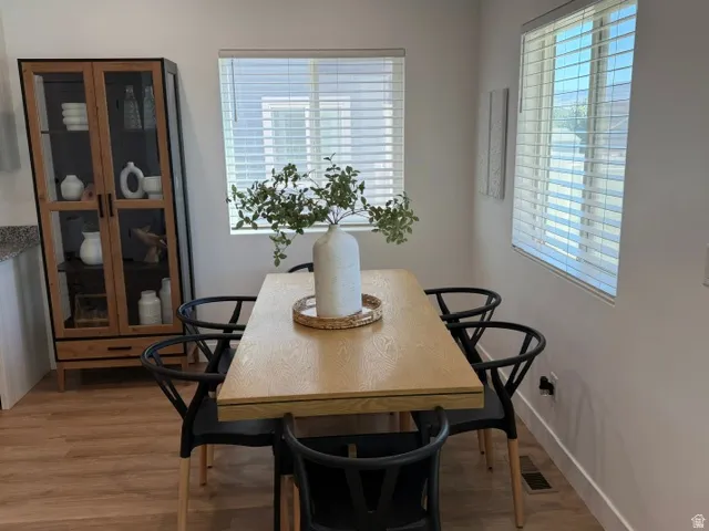 Wood-finish flooring, multiple windows with blinds, and white painted walls